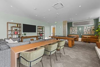 A modern living room with a long wooden table and grey chairs.
